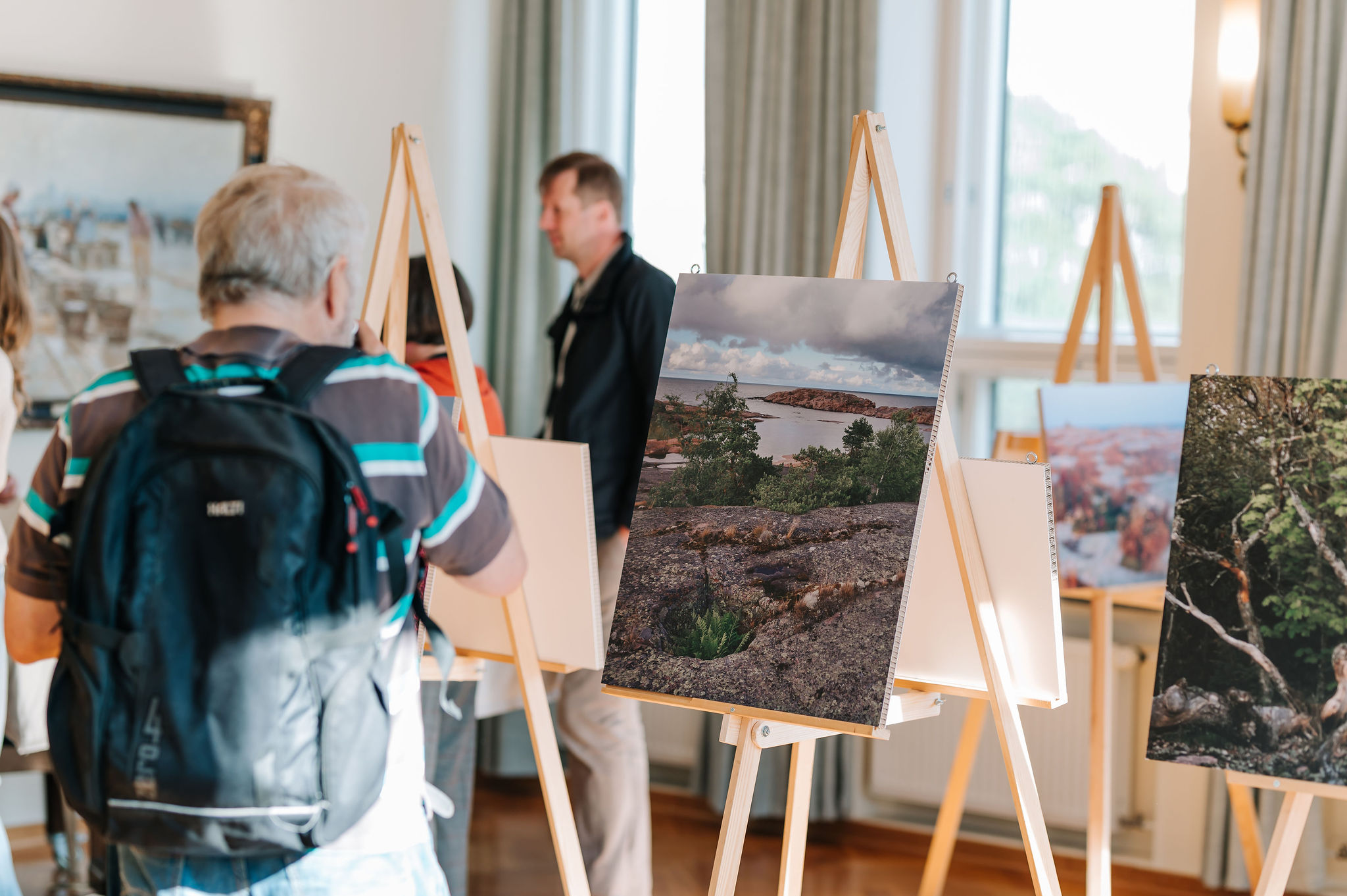 Ihmisiä katsomassa meriaiheisia valokuvia taidenäyttelyssä